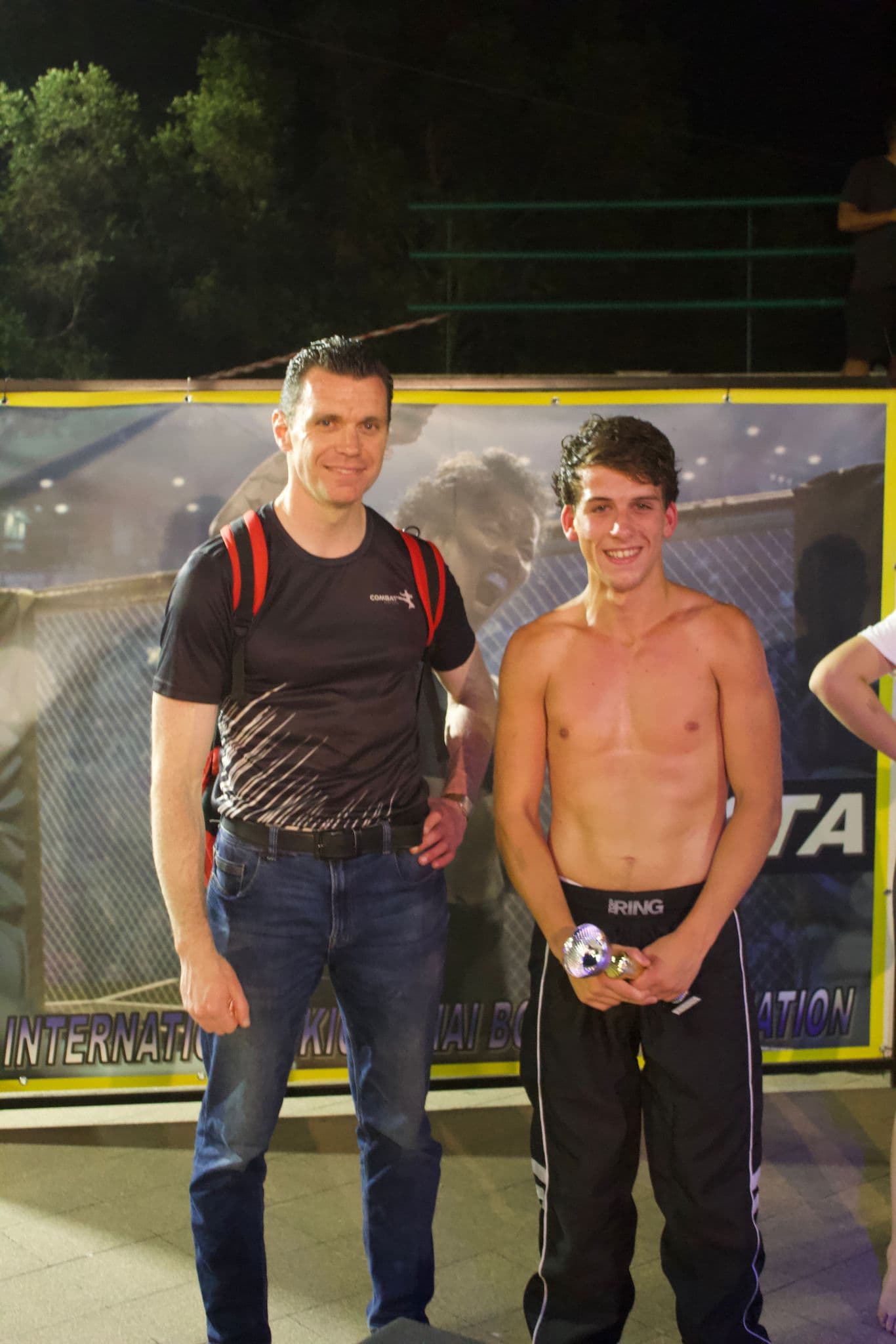 Atleta IKTA con lo staff davanti alla gabbia MMA