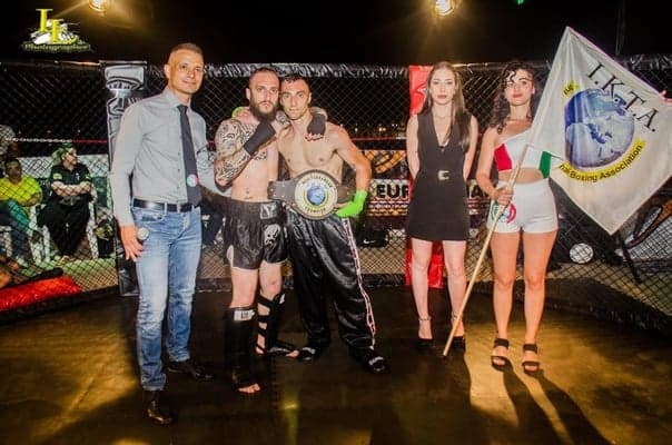 Atleti IKTA con la cintura del titolo davanti alla gabbia MMA