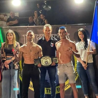Campione IKTA premiato con la cintura del titolo insieme allo staff