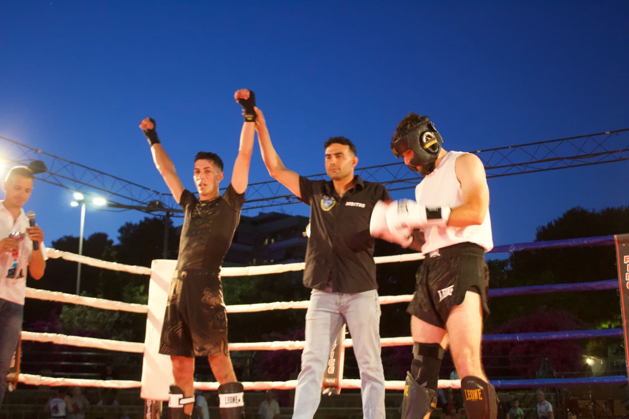 Atleta IKTA vincitore proclamato sul ring al tramonto con il braccio alzato